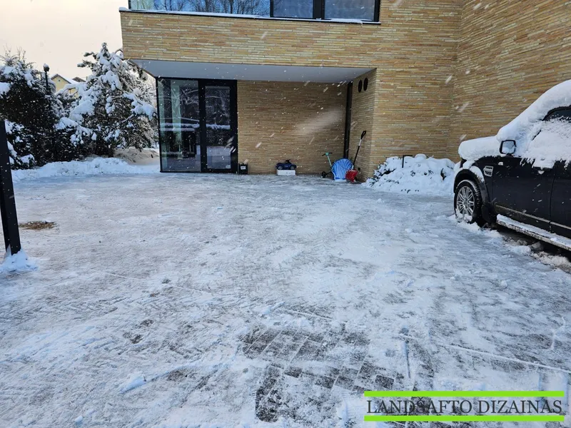 Mini krautuvu nuvalytas privataus namo kiemas su trinkelių danga, sniegas sustumtas į pakraščius